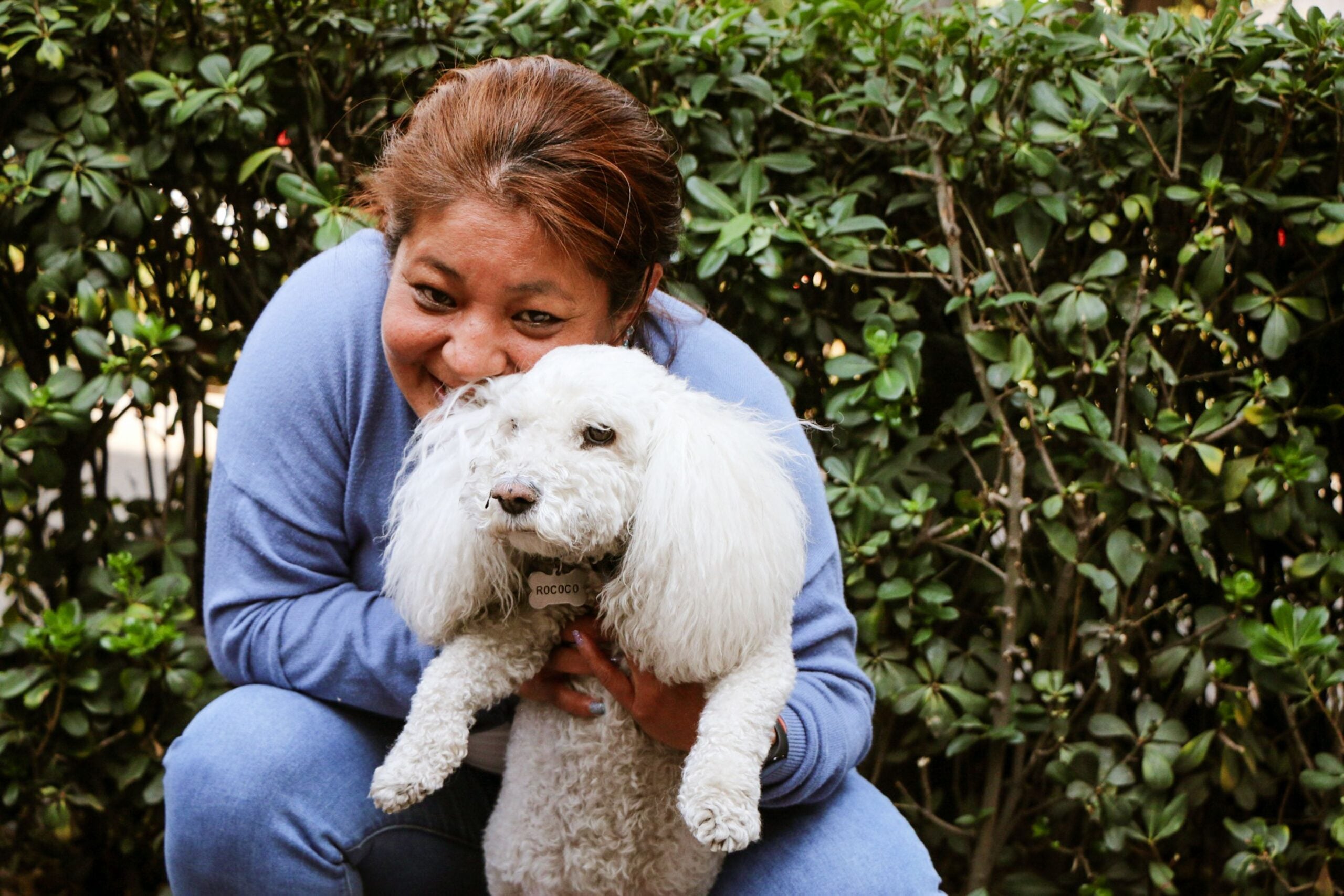 Smiling dog owner with her dog after a grooming appointment